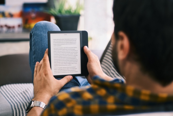 young-man-reading-ebook-with-ereader-on-couch-UNX2FUS-min